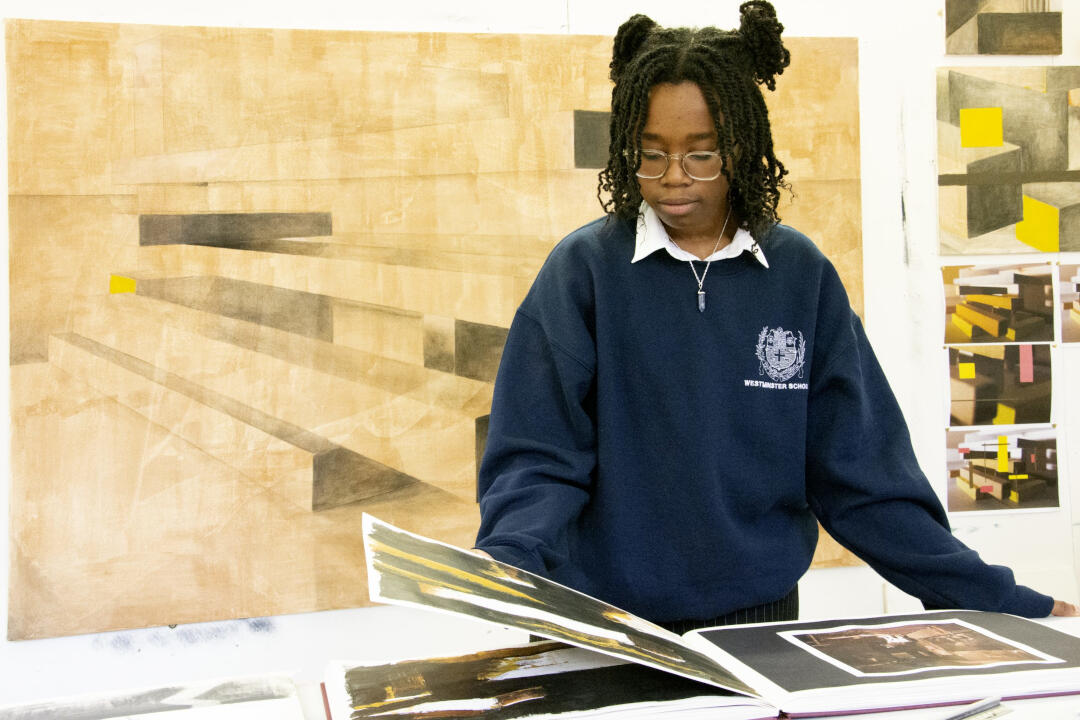 A girl looking through a portfolio with her art behind her
