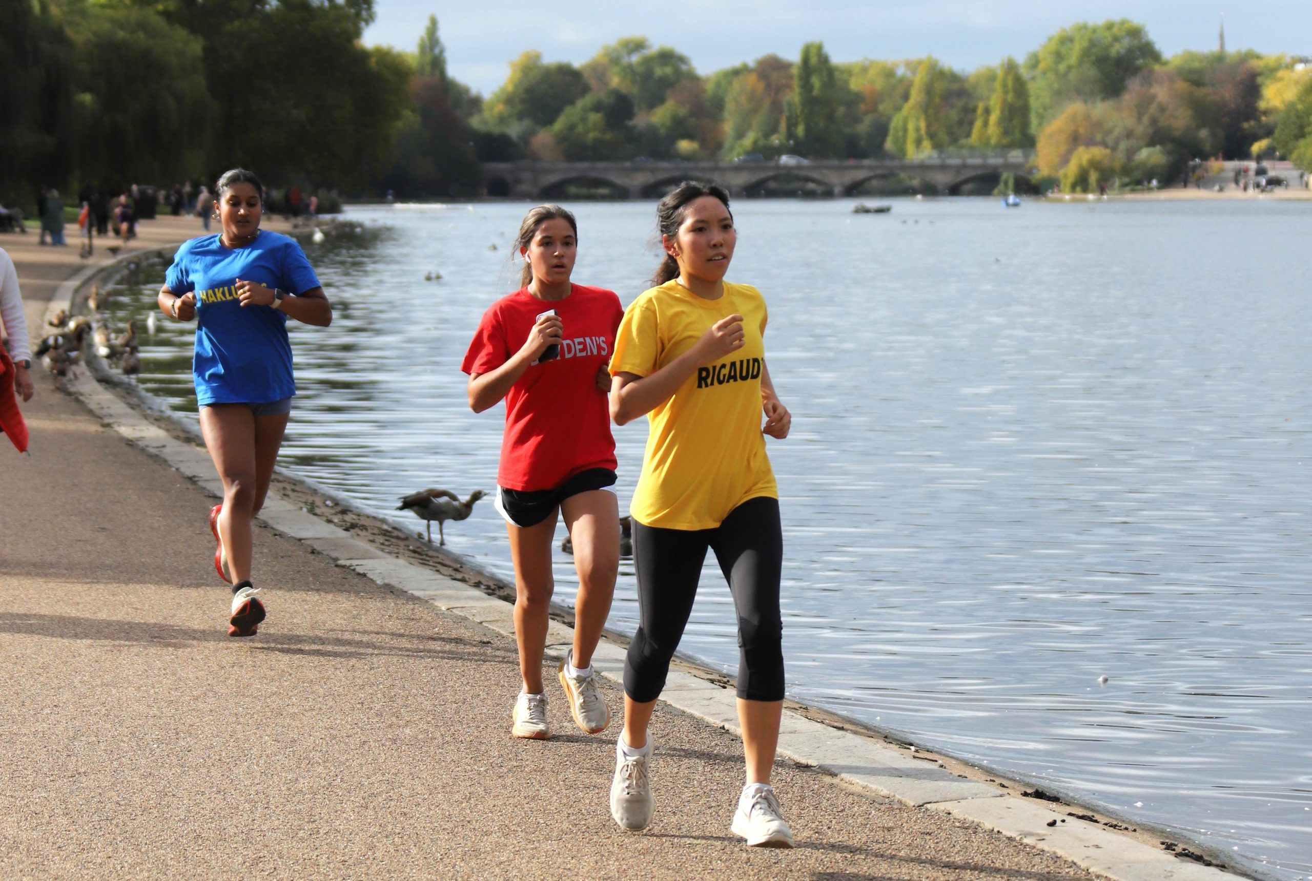 Three girls running in the long distance races around the lake in Hyde Park