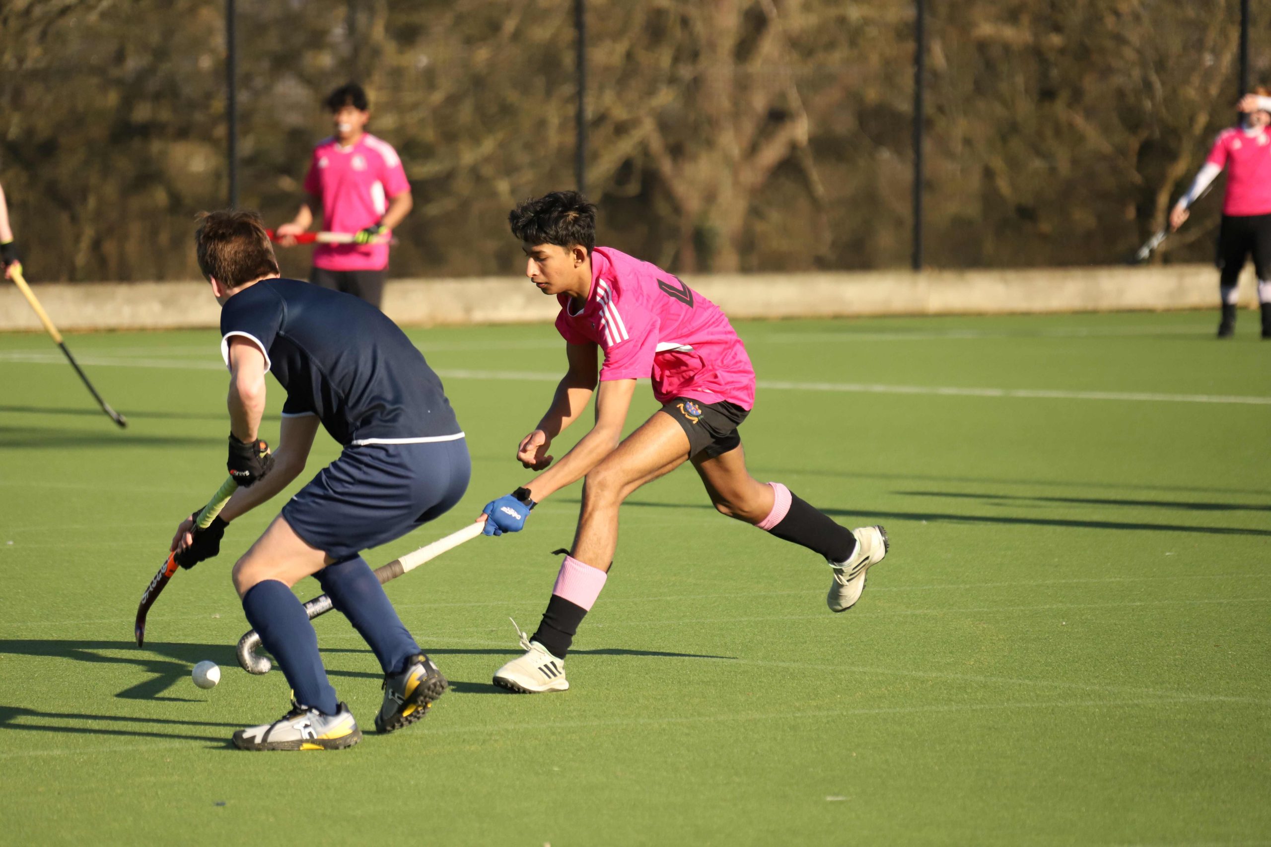 A Westminster pupil tackling another pupil on the hockey pitch