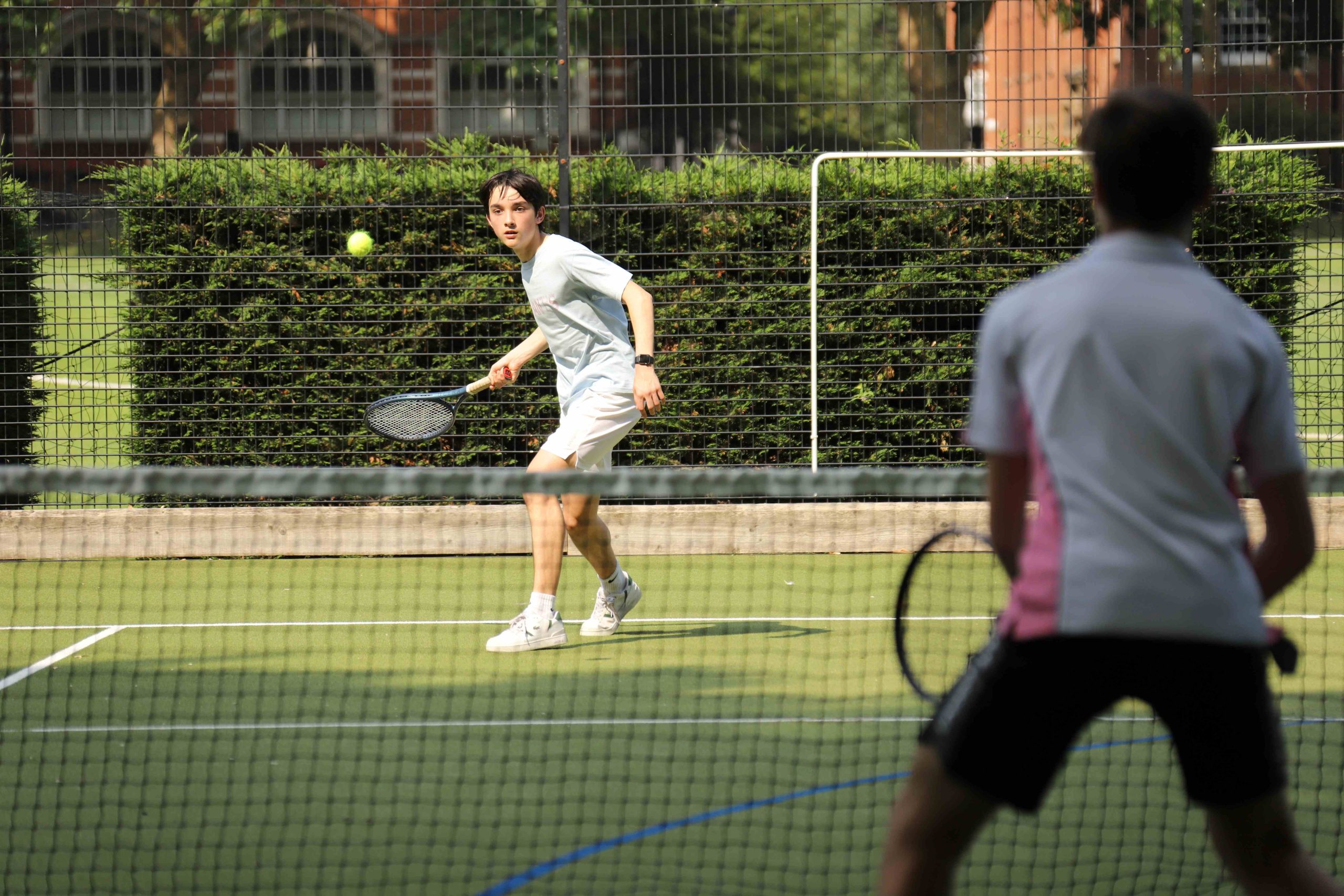 Boy just about to hit tennis ball over the net, using a forehand