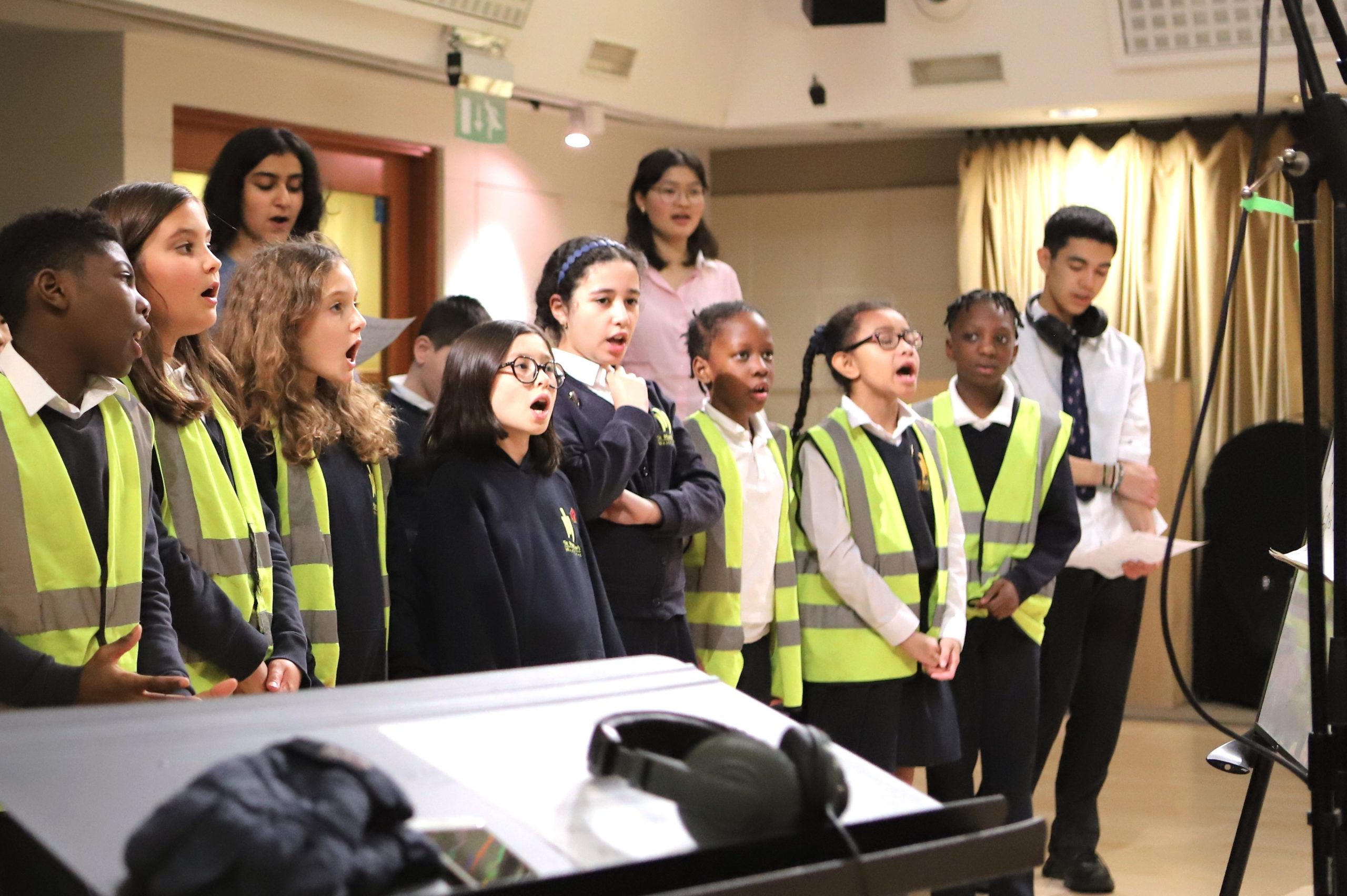 Pupils from a local primary school singing with Sixth Form volunteers in the music department