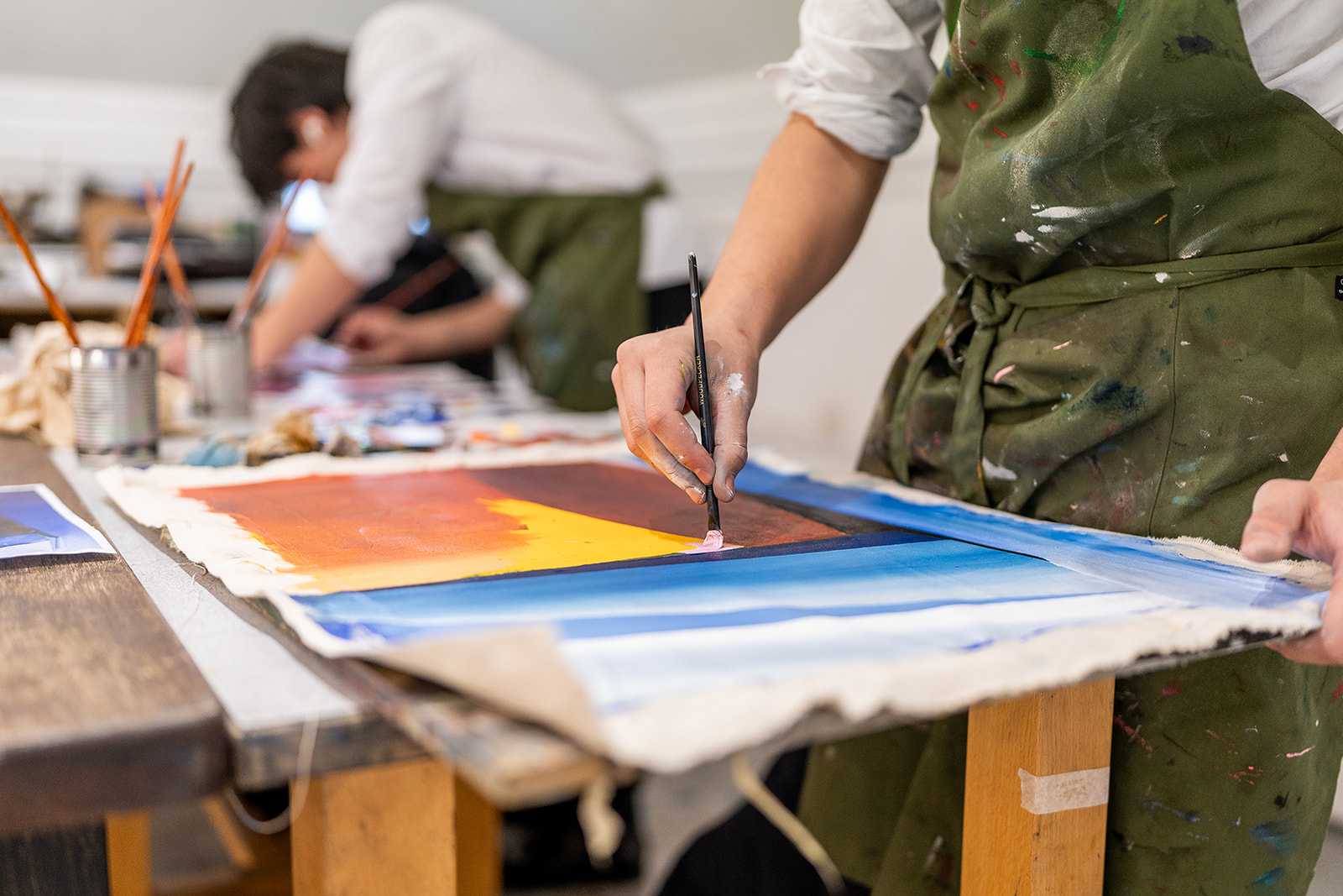 Two boys painting on paper at a table