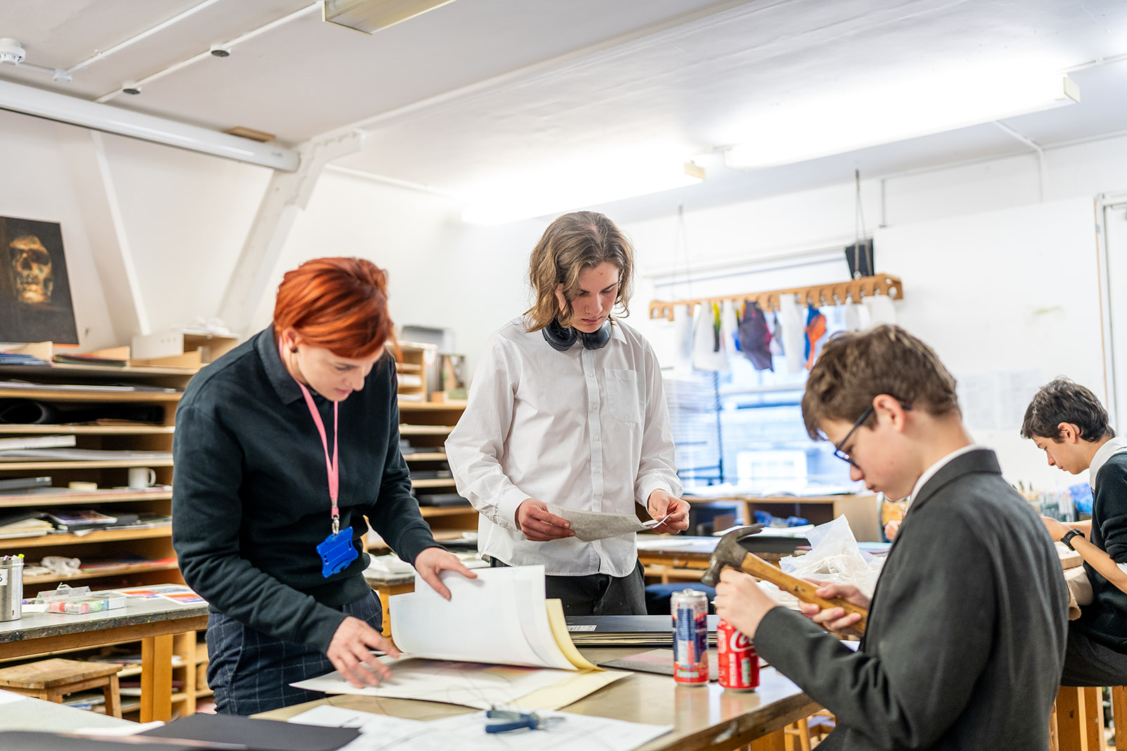 An art teacher with two boys in a studio, looking through books and studying tin cans
