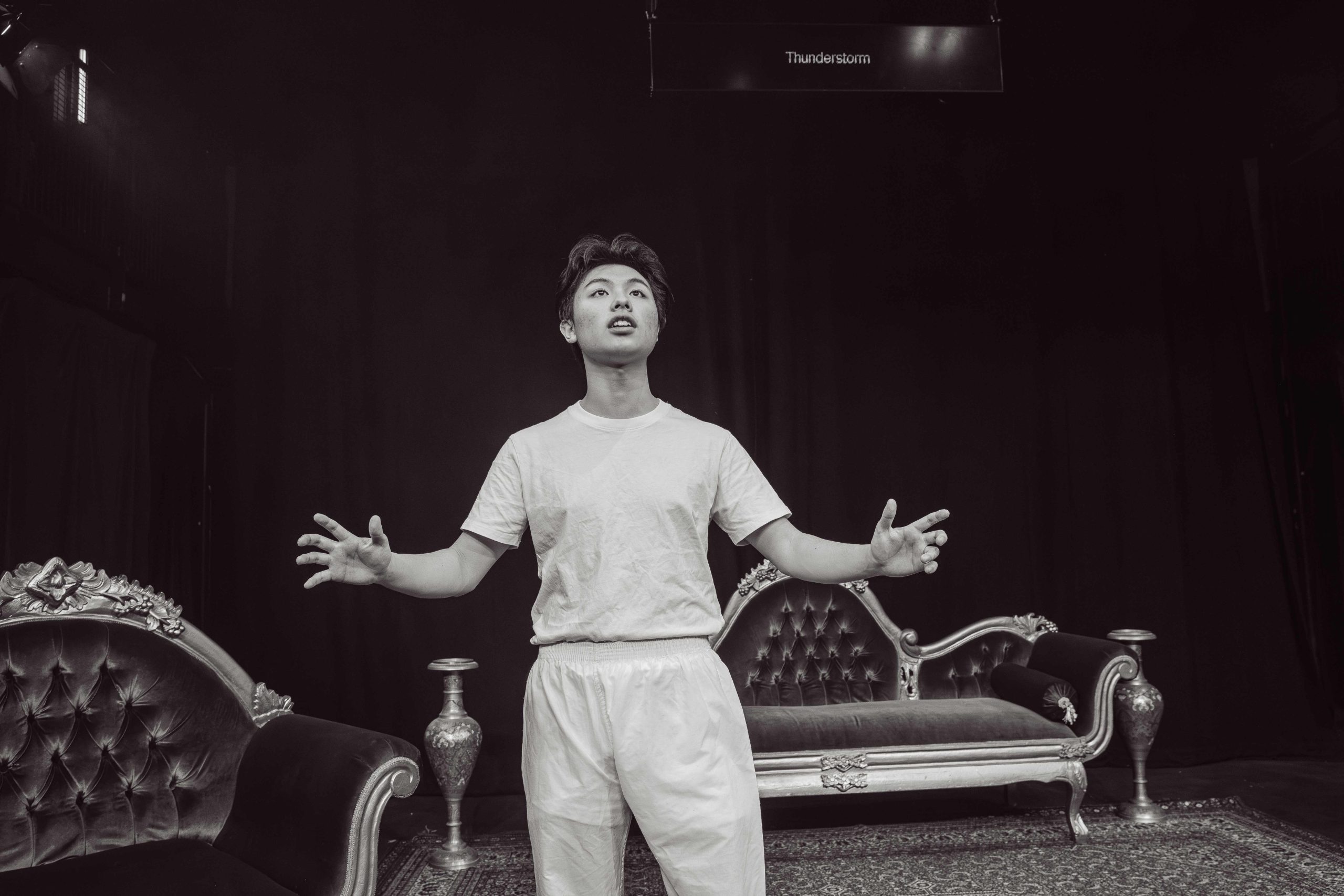 A boy on stage with arms out, looking up