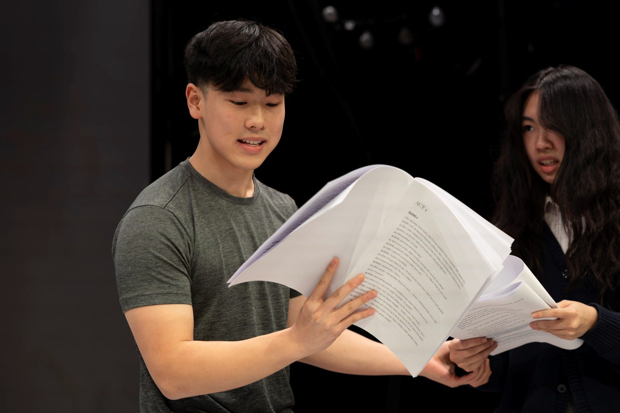 A boy and a girl rehearsing with scripts in hand