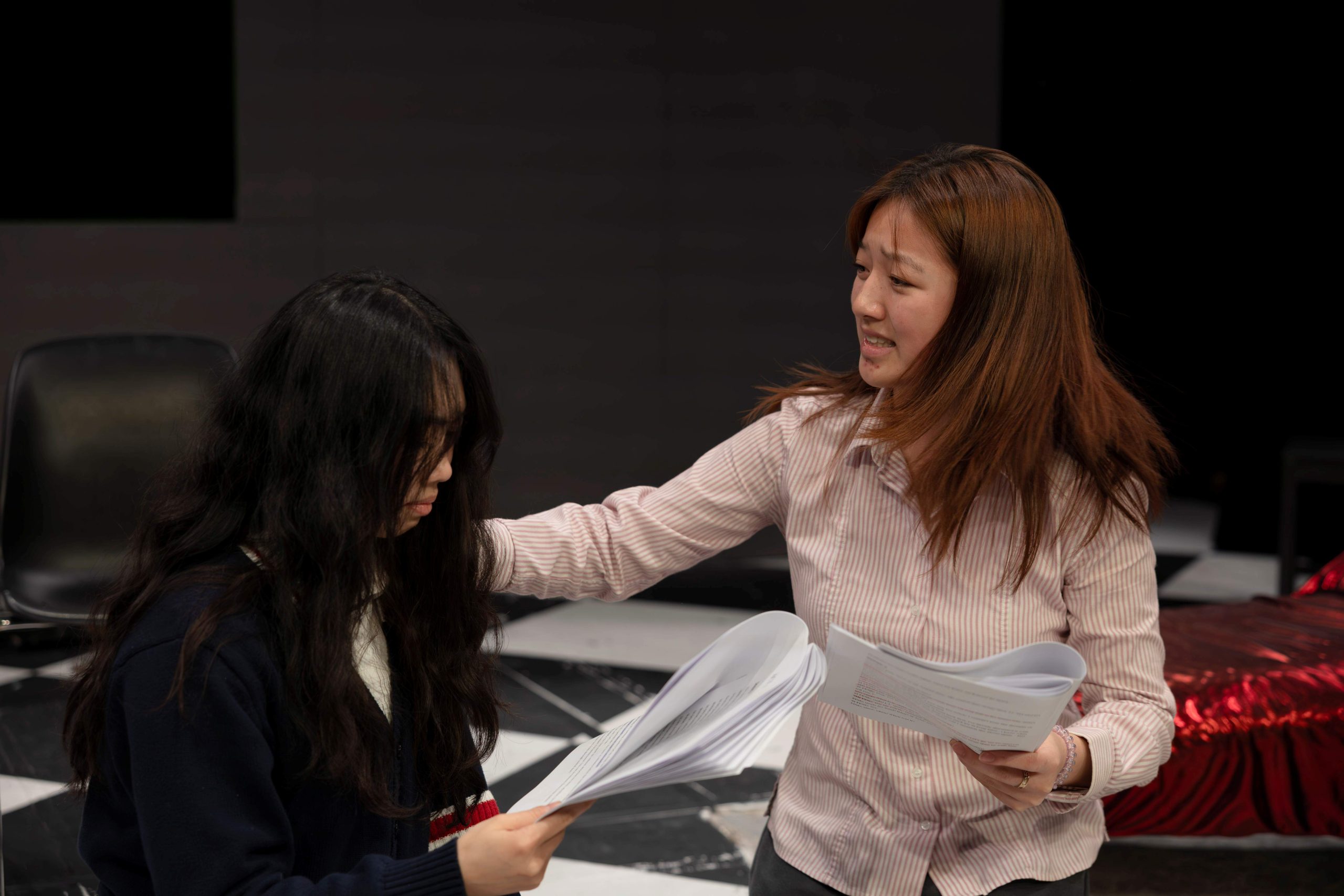 Two girls, animated and rehearsing with scripts