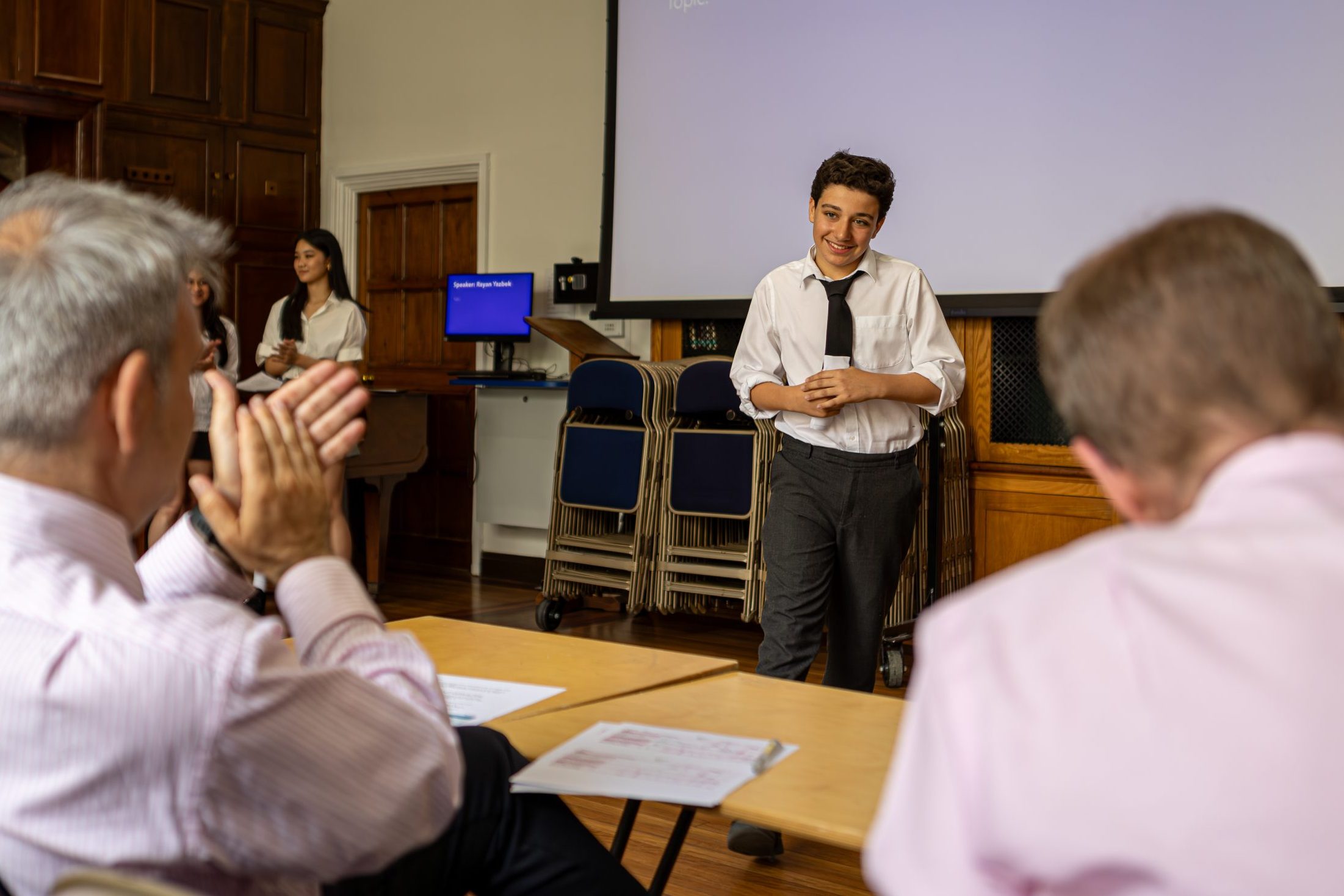 A speaker smiling at the judges as he is being applauded