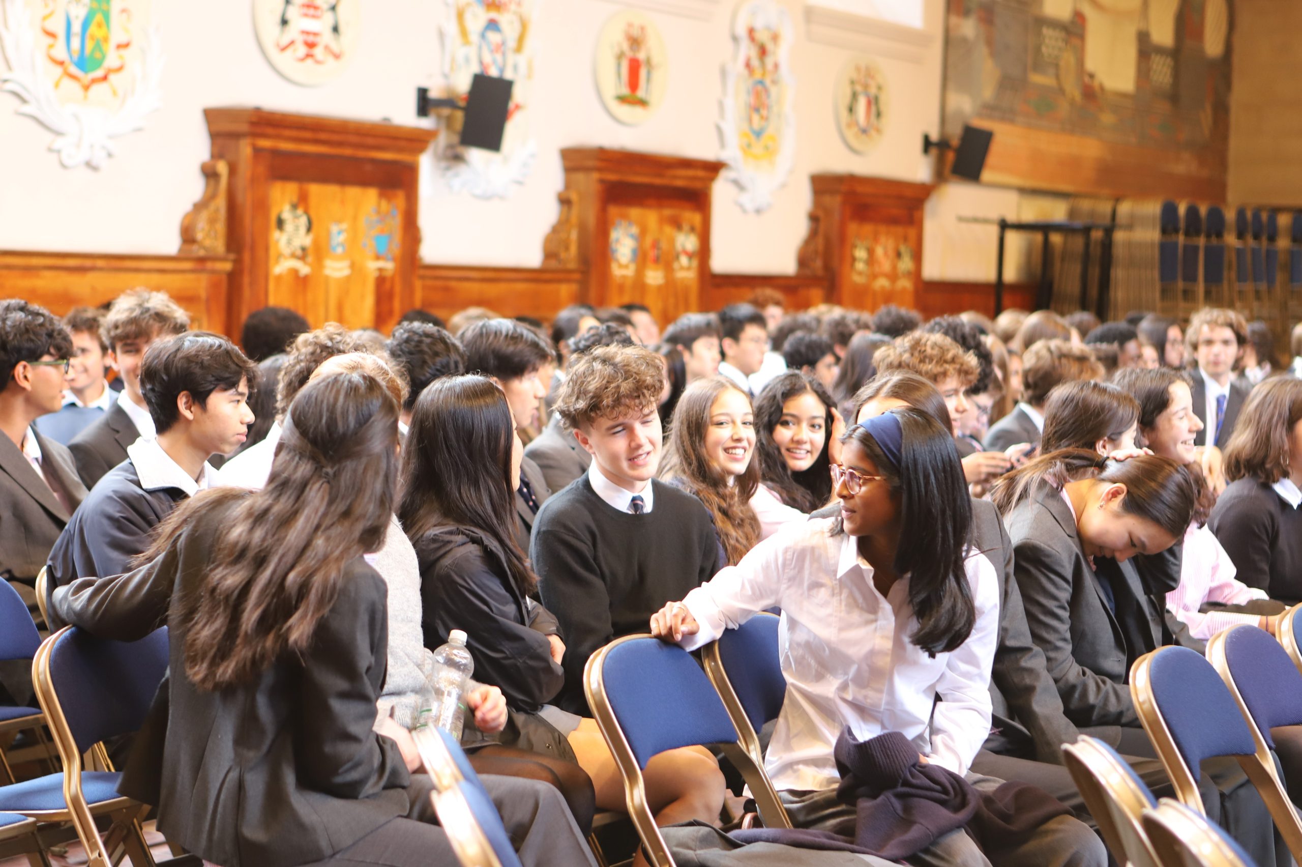 Rows of Sixth Form boys and girls turning round to talk to one another prior to listening to a talk by Bijan Omrani on his new book 'God is an Englishman' at Westminster School.
