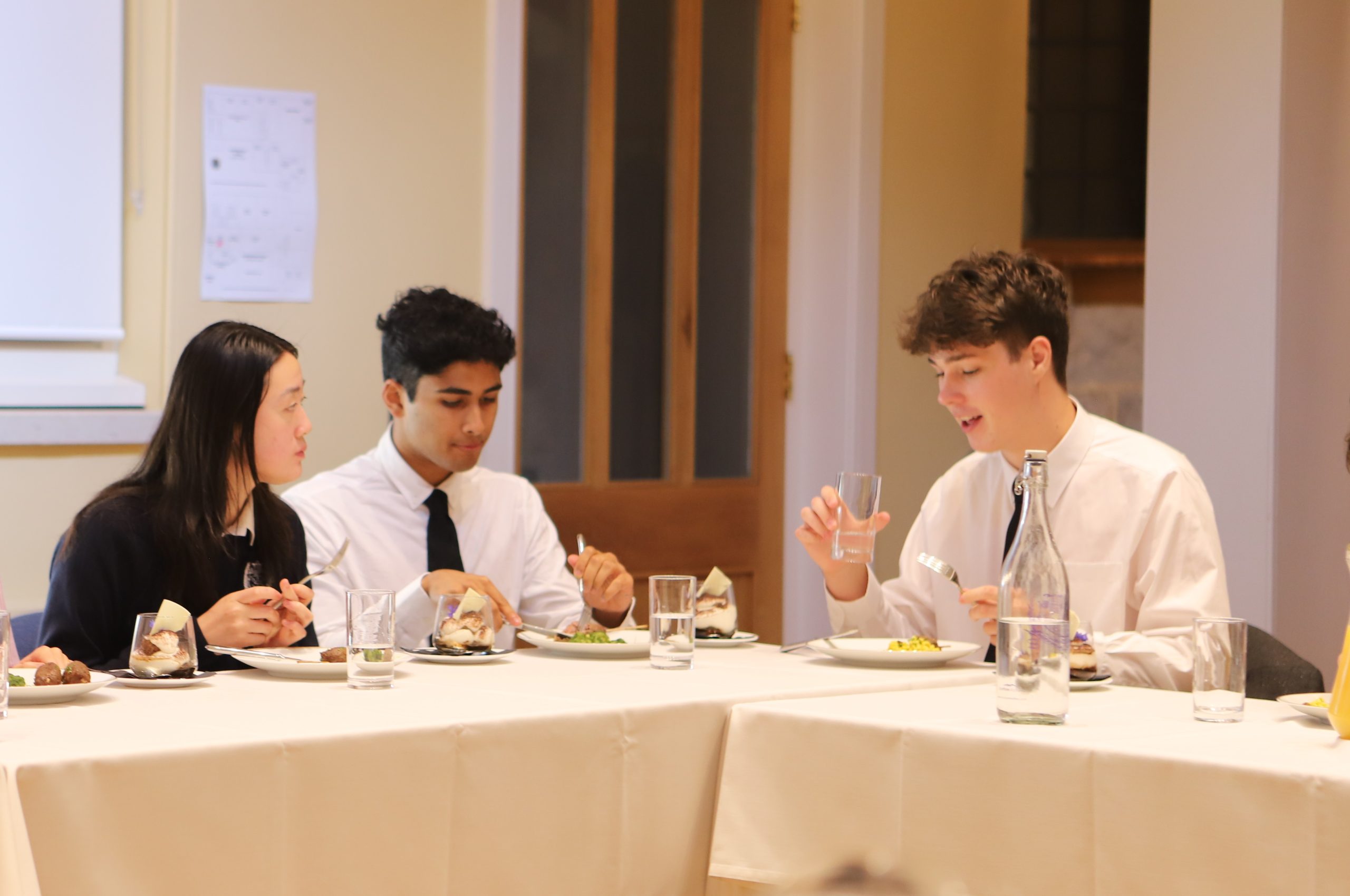 Three girls and boys eating together and chatting around a table at the Locke Lunch, following Bijan Omrani's talk on his new book 'God is an Englishman' at Westminster School.