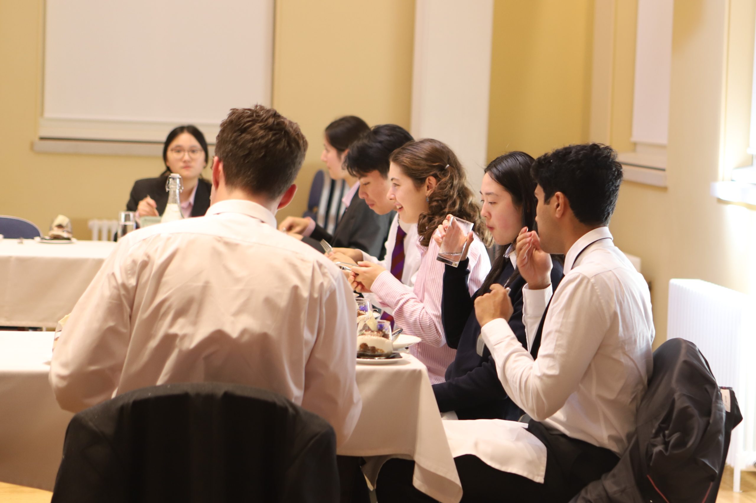 Seven girls and boys eating together around a table at the Locke Lunch, following Bijan Omrani's talk on his new book 'God is an Englishman' at Westminster School.