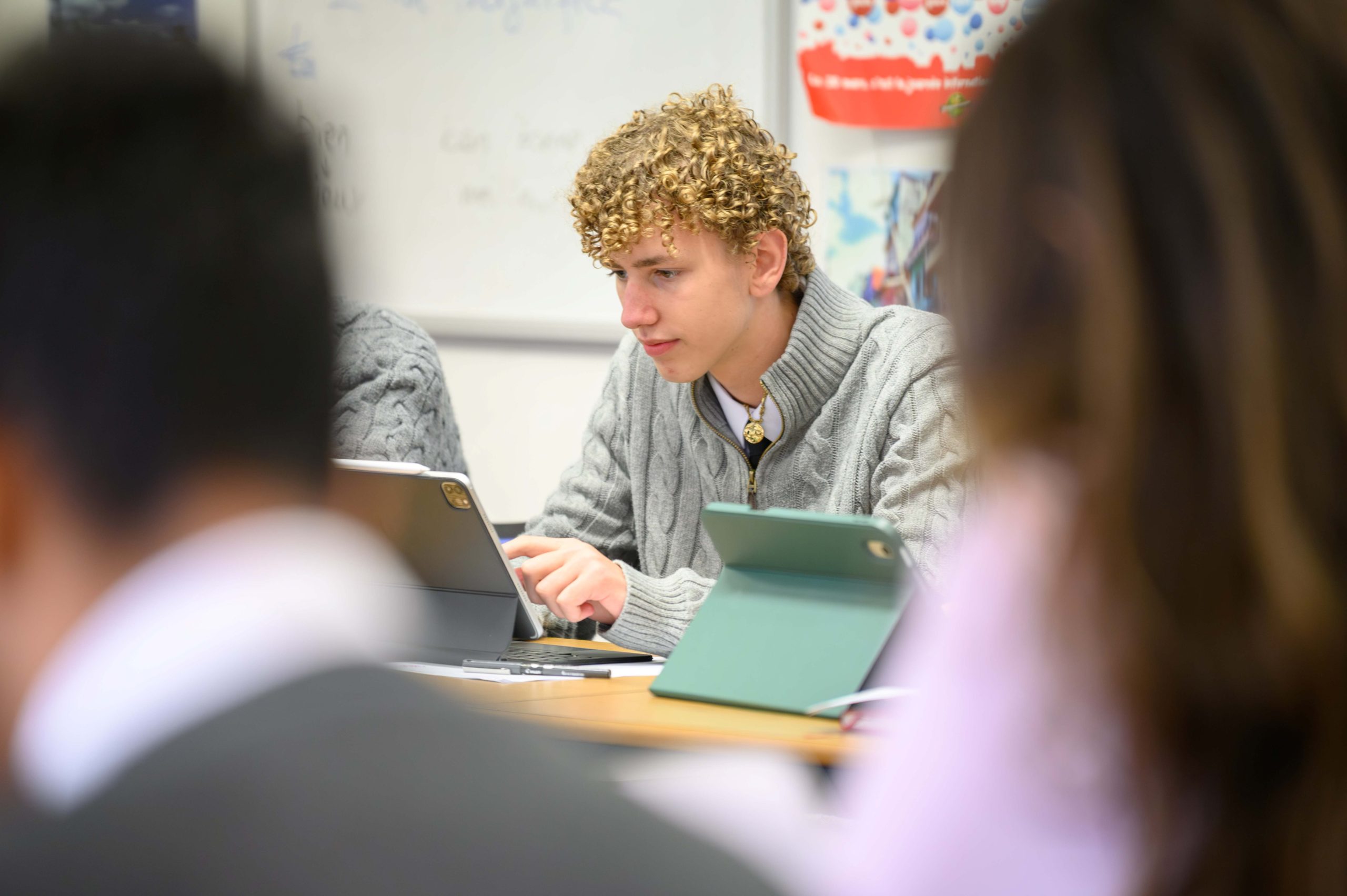 A boy writing on his tablet in class