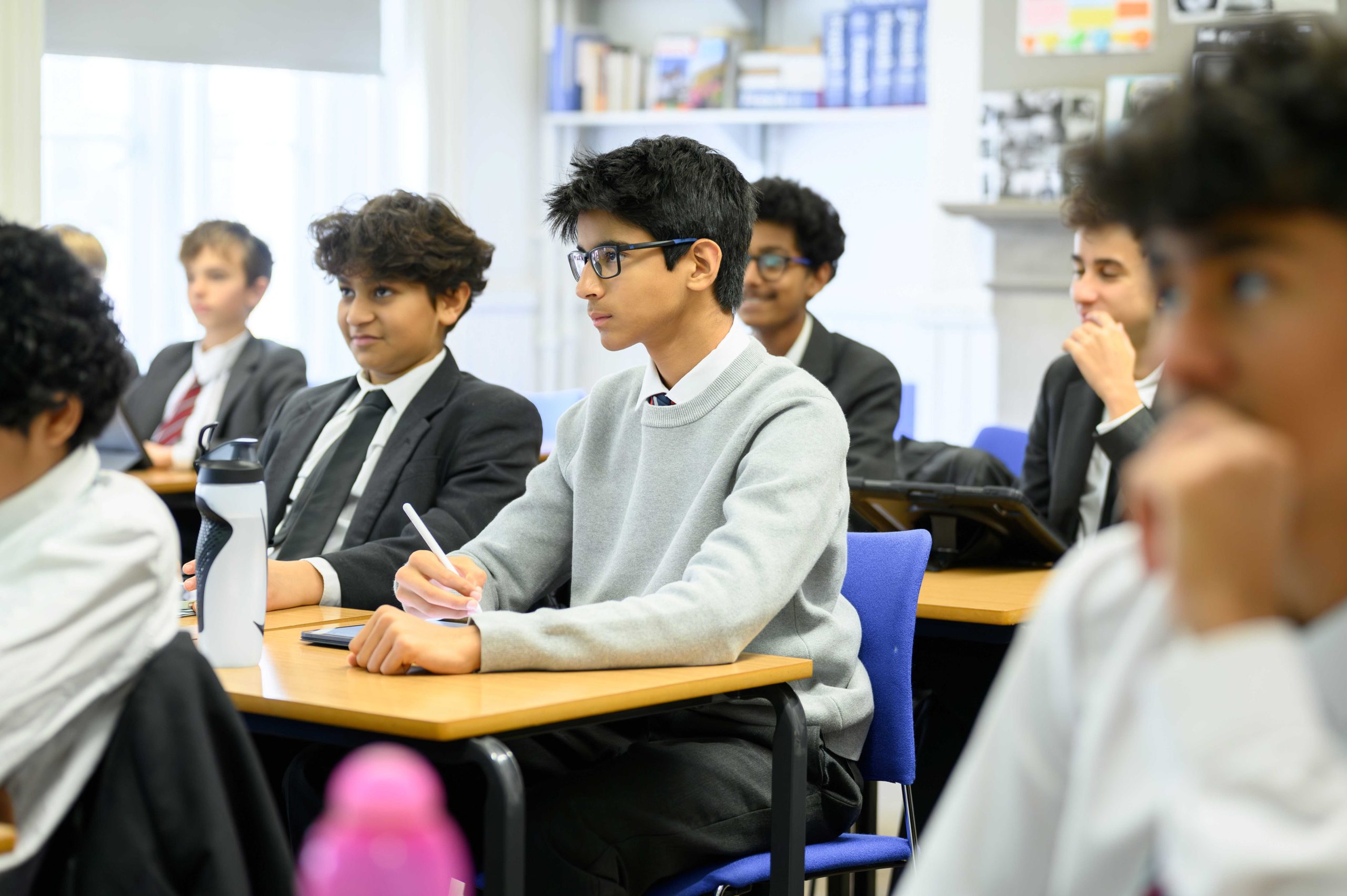 A group of boys sat at desks in a French classroom, listening to the teacher