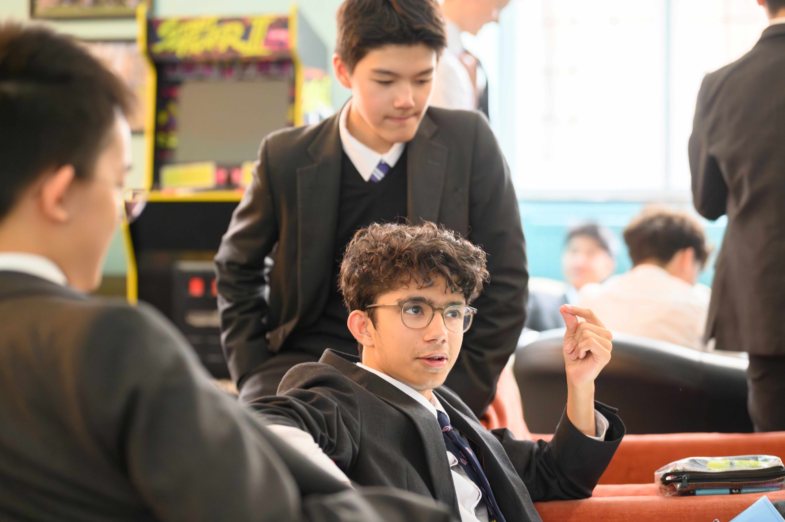 A boy on the couch in conversation with another boy sat on the backrest behind him