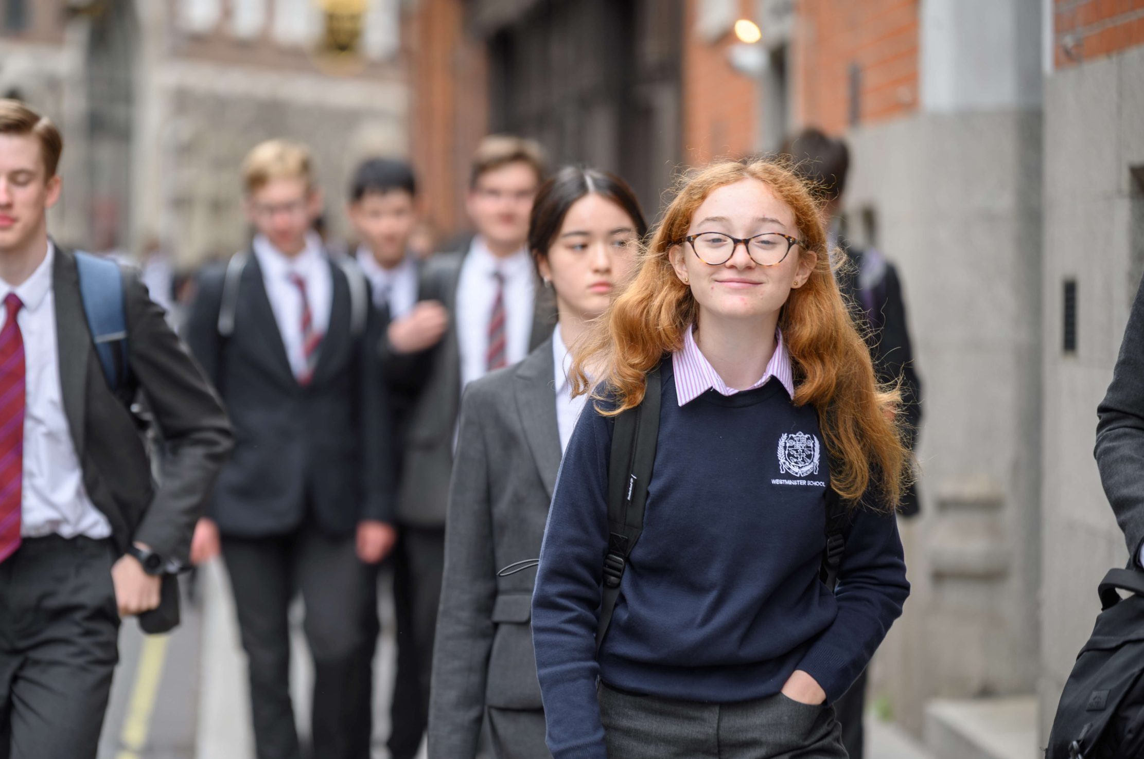Pupils walking towards the camera from Dean's Yard to other school buildings, the girl at the front is smiling