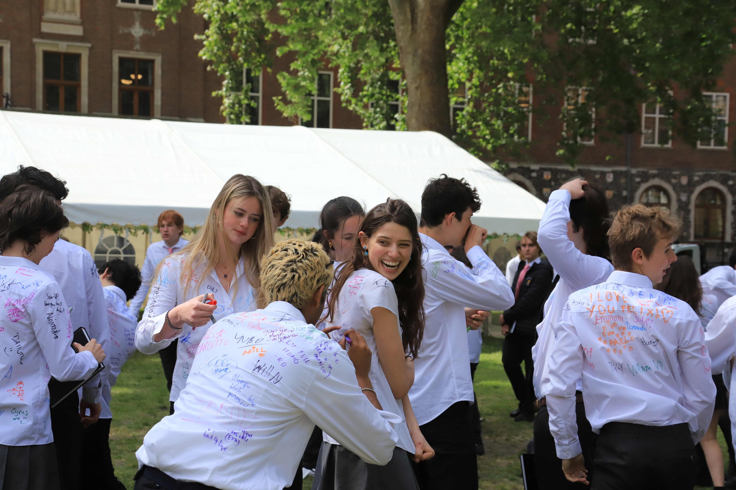 The Remove brunch, a large group of pupils signing one another's shirts on the last day of school before exams, in Dean's Yard with the marquee behind them