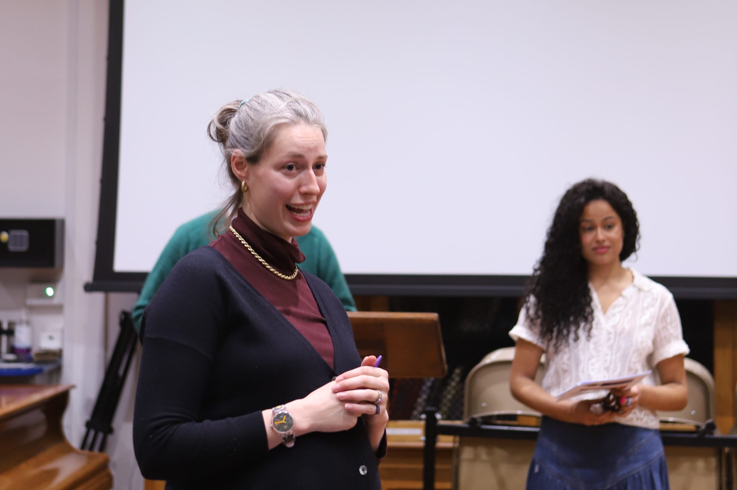 Art History teacher smiling, standing at the front, with judge behind her.