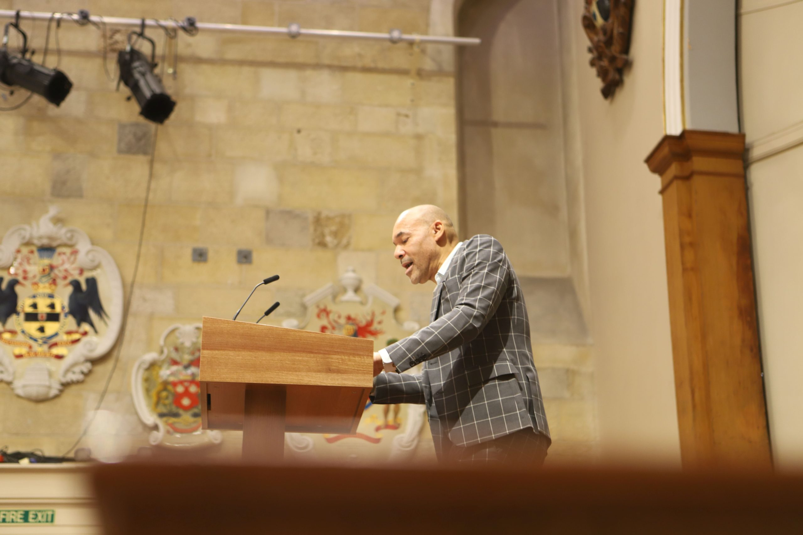 Basi speaking on stage in front of a lectern at a Locke lecture