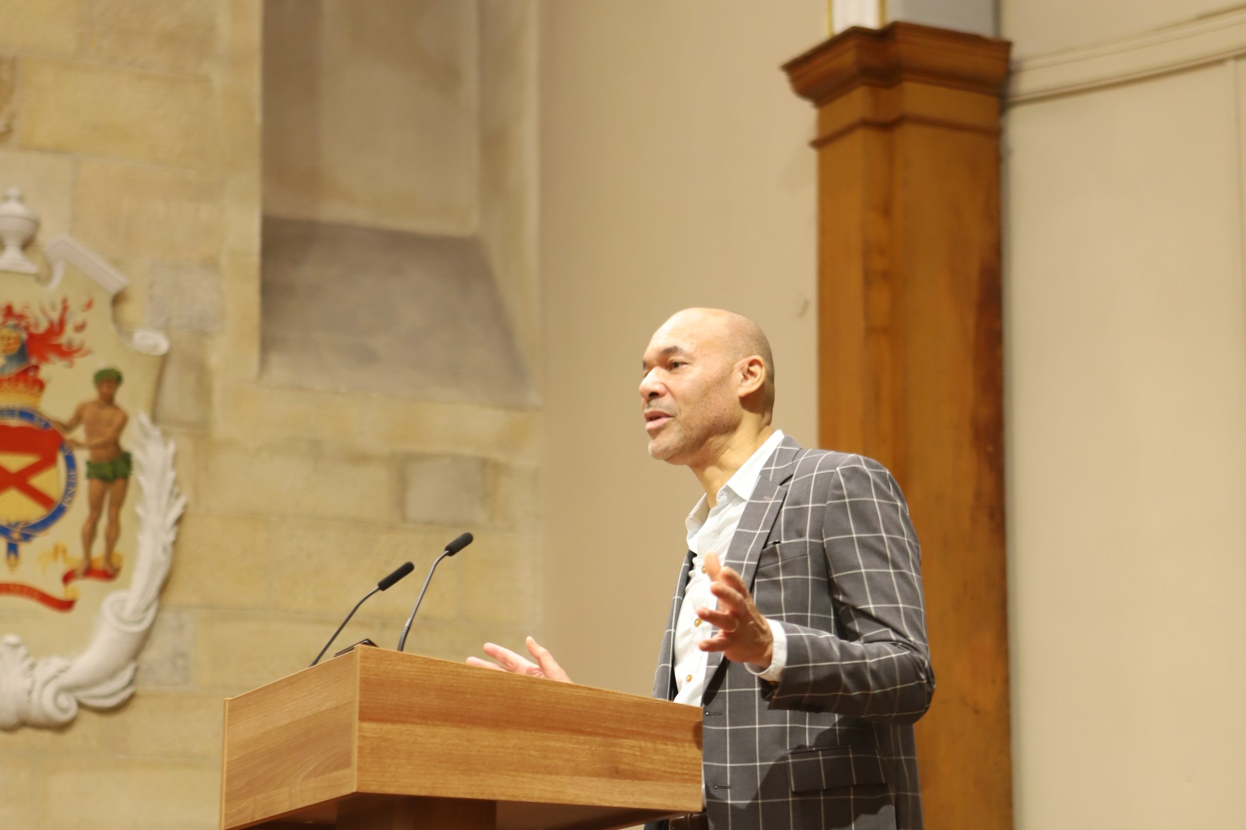 Basi speaking on stage in front of a lectern at a Locke lecture