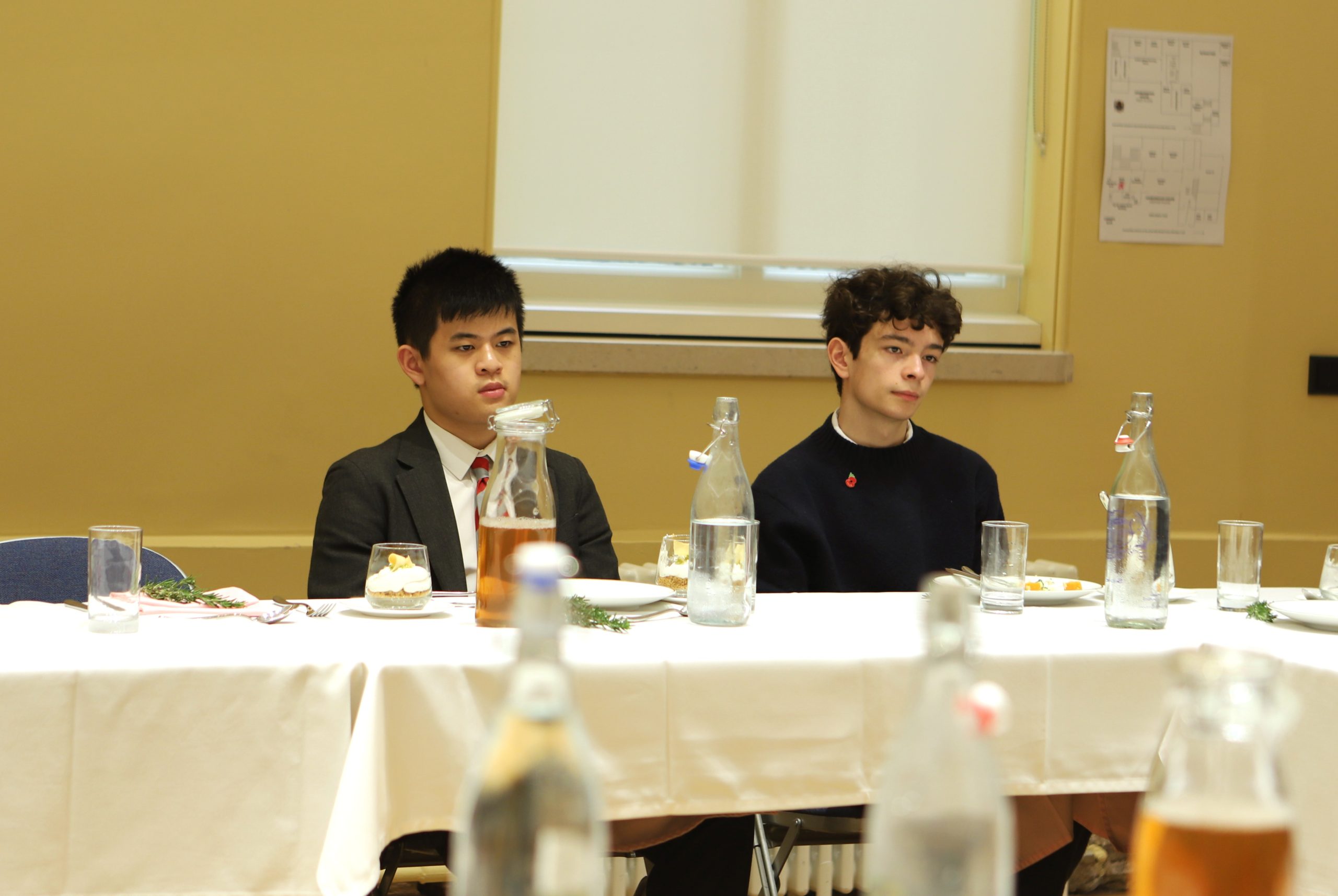 Two boys listening to Basi speak at the communal table in the Locke lunch