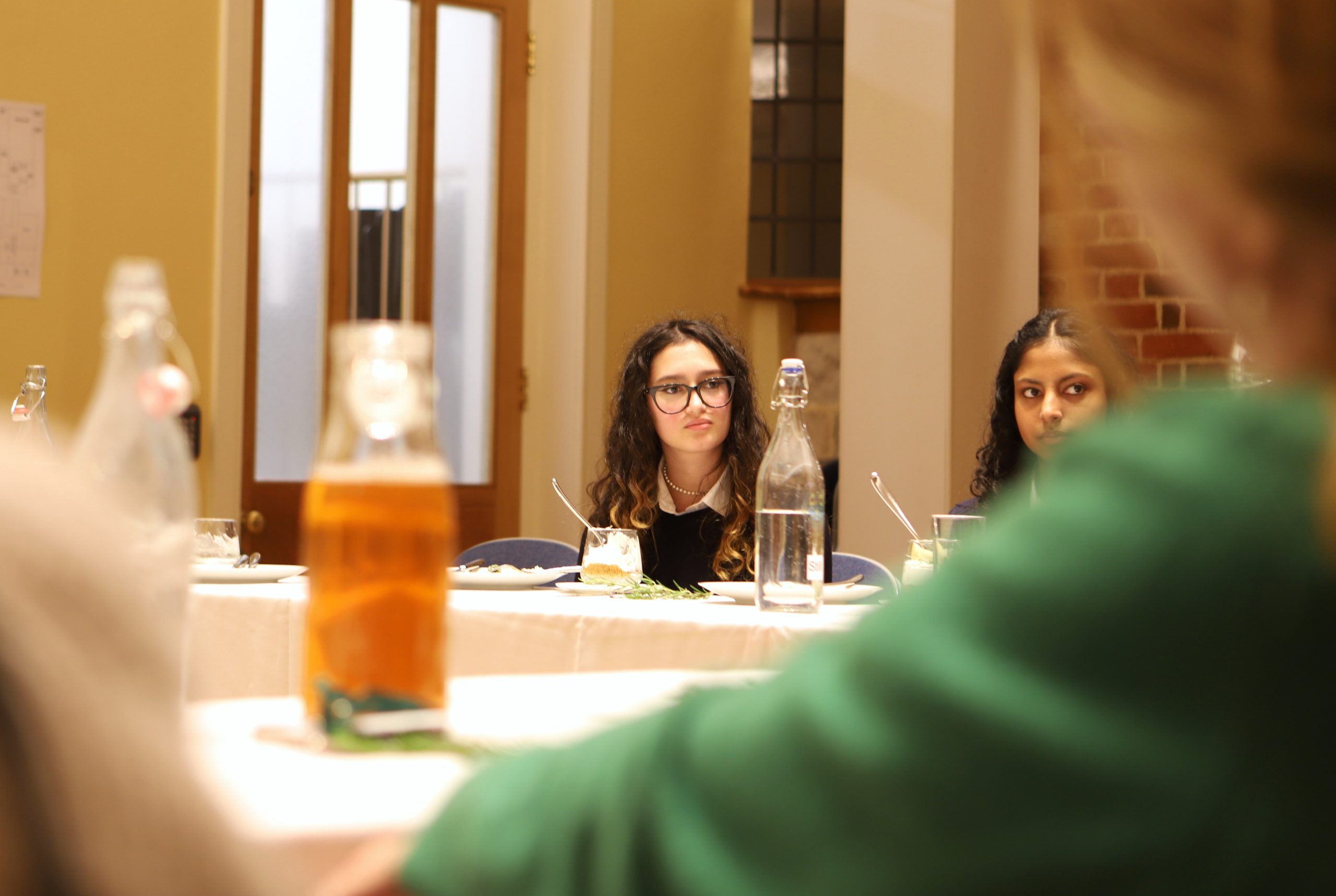 Two girls listening to Basi speak at the communal table in the Locke lunch