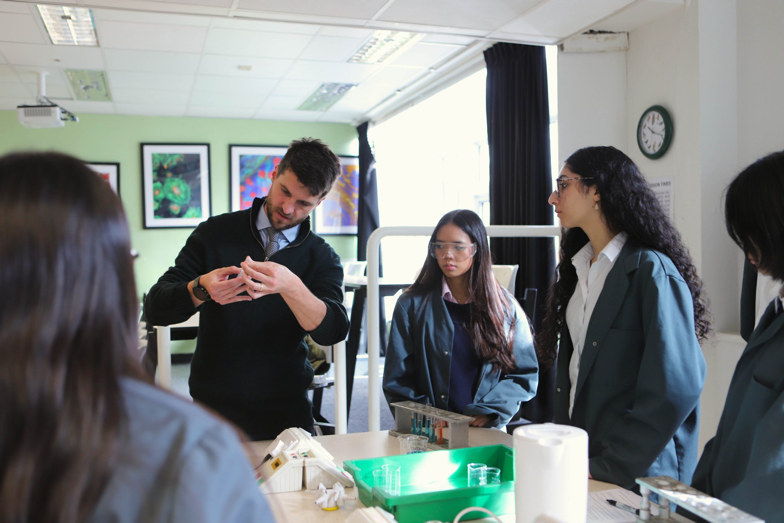 A biology practical with the teacher demonstrating to three girls in the lab