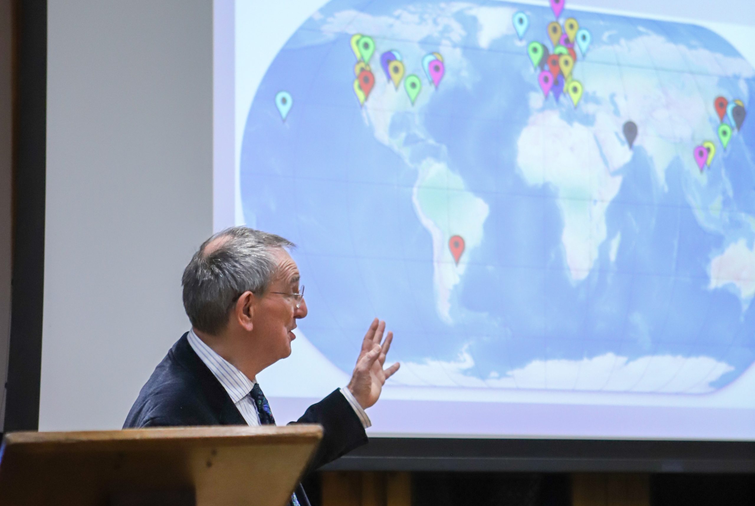 Professor Lockwood with the map on the screen behind him, charting all of the places he has worked in the world