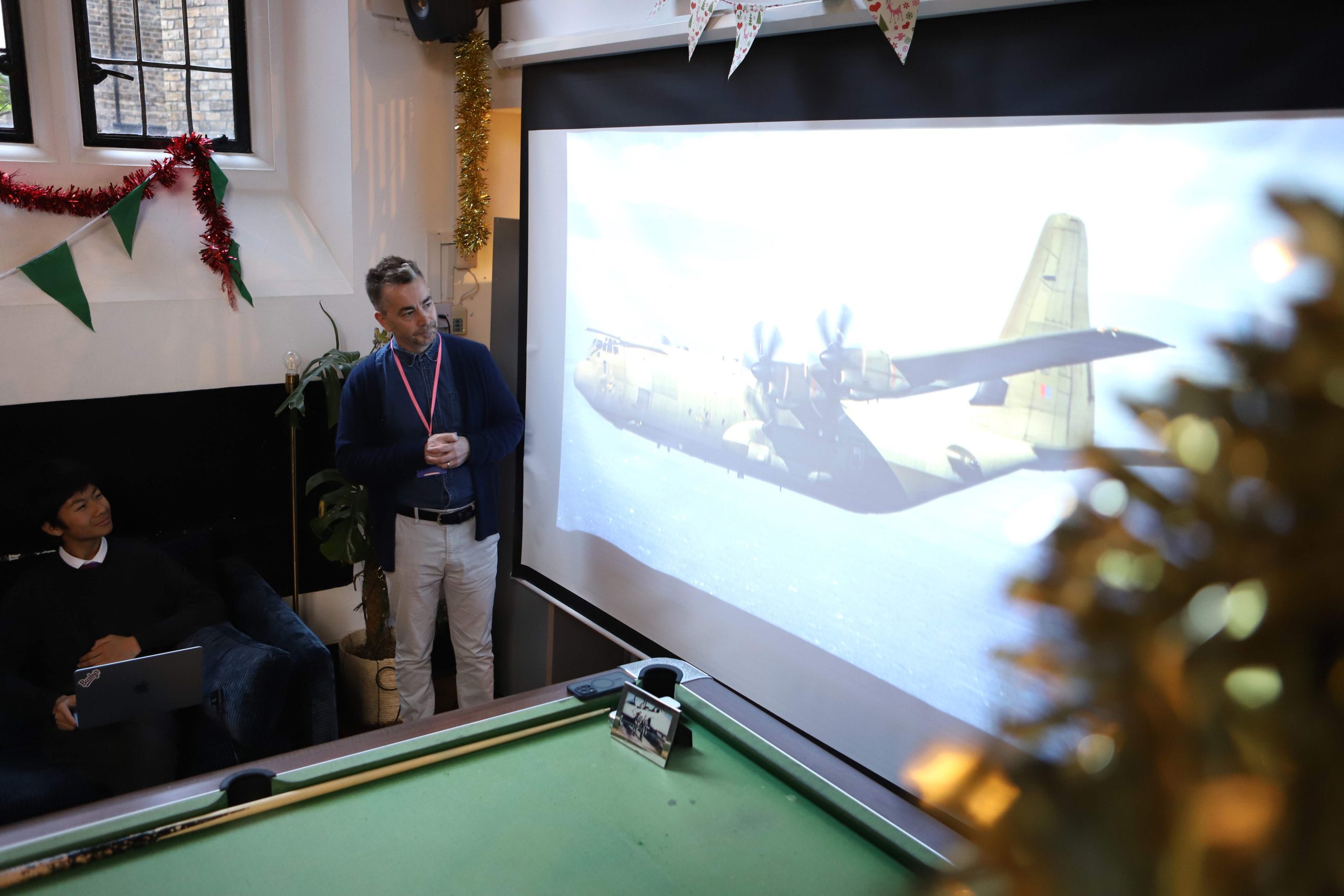 Chris in front of an image of a large plane on the screen.