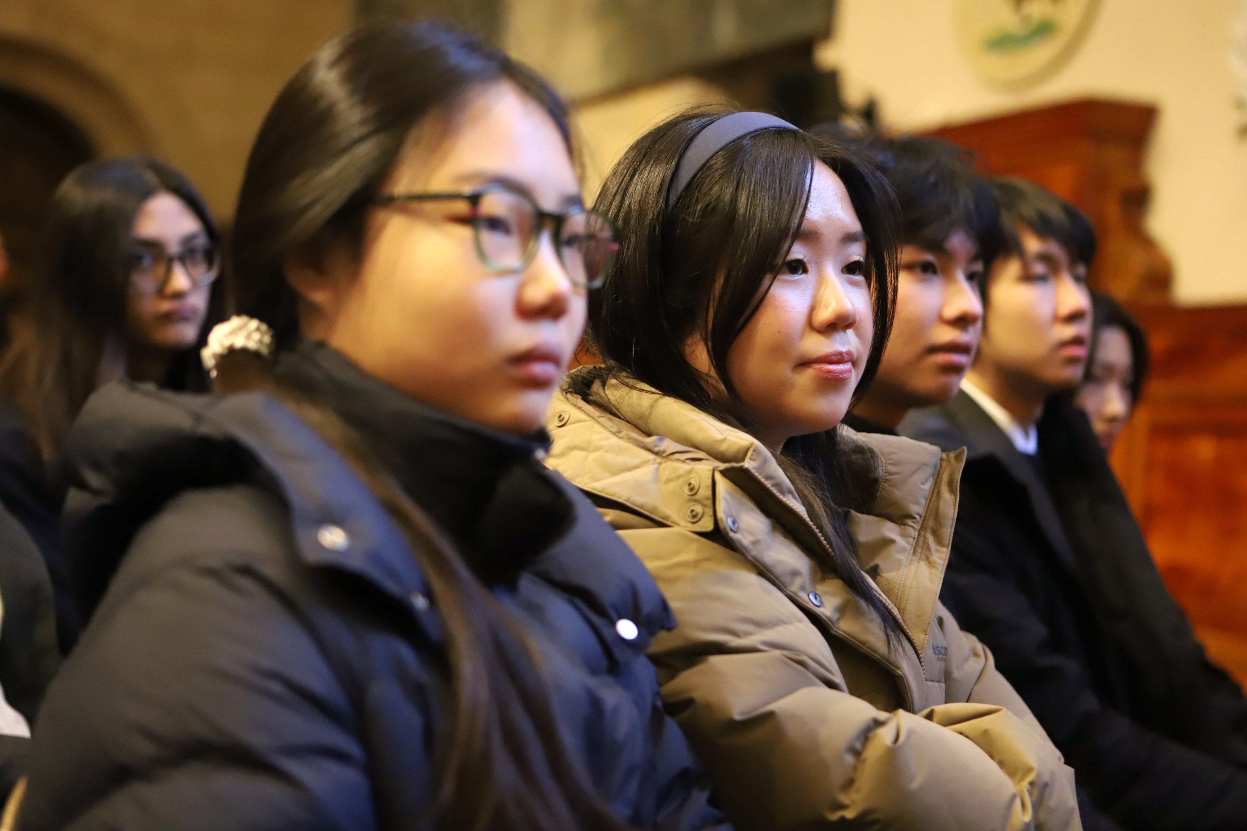 Four pupils in a row watching the talk, the girl in the middle is smiling