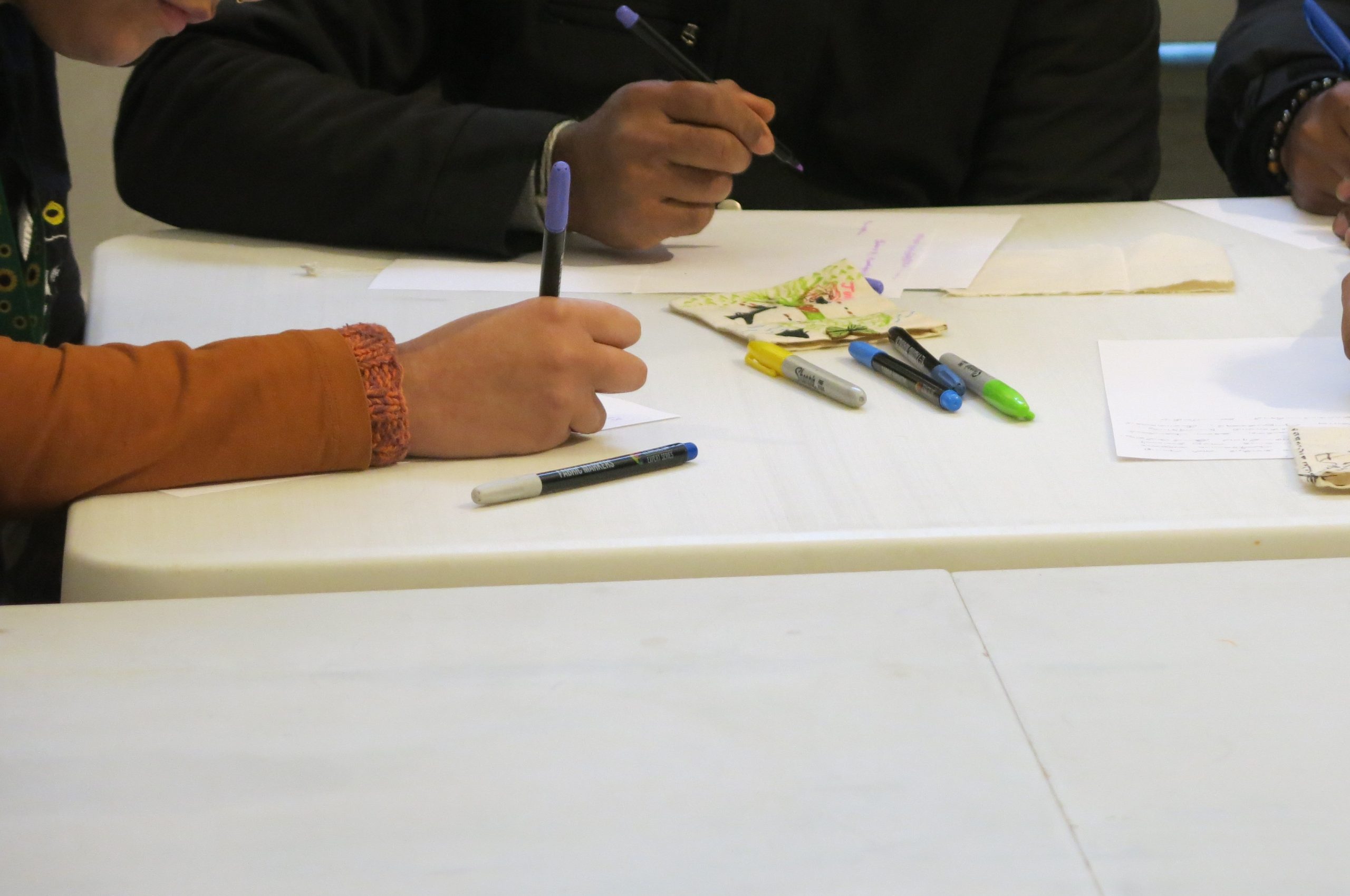 Hands drawing at a table