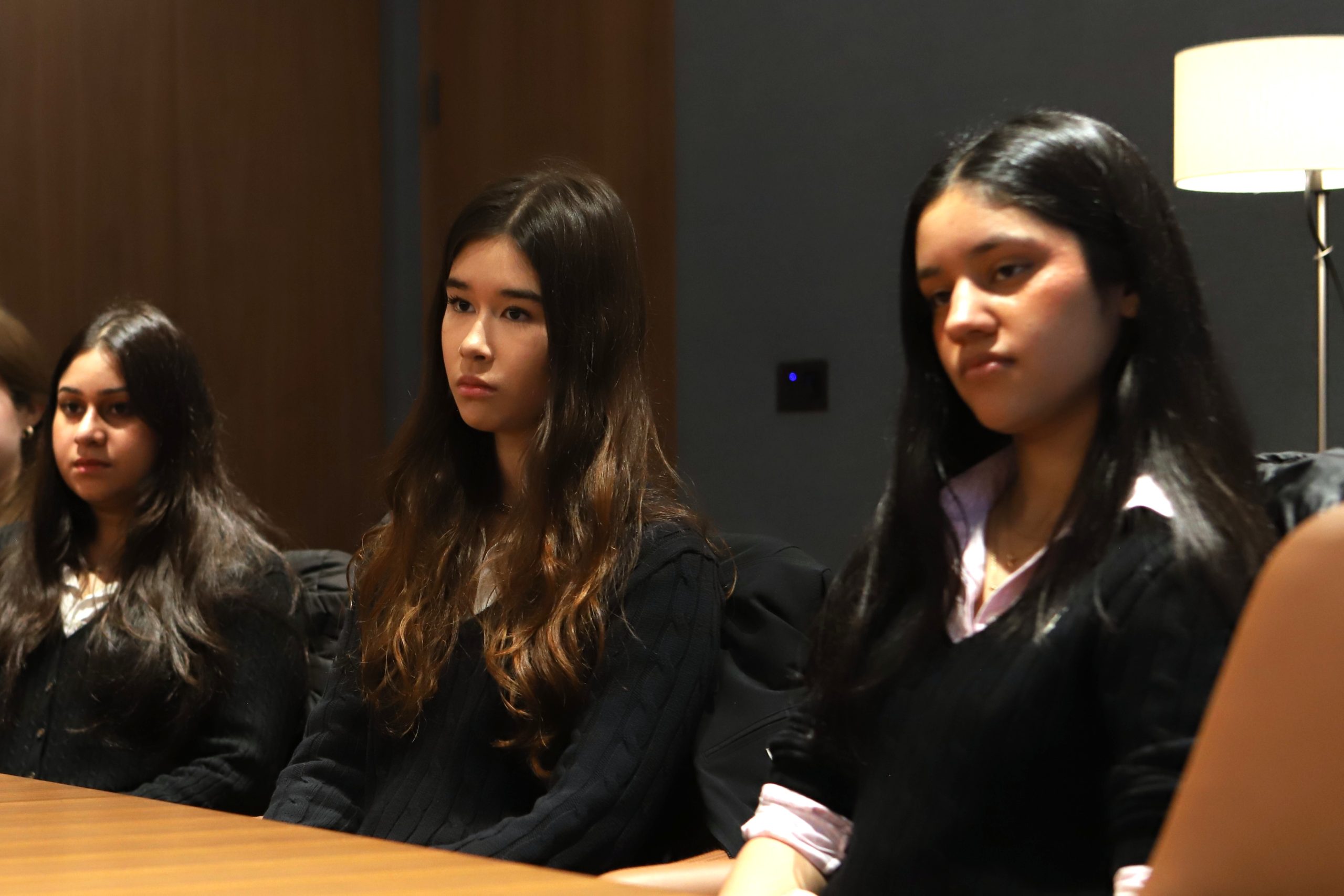 Three girls listening at the table in the board room