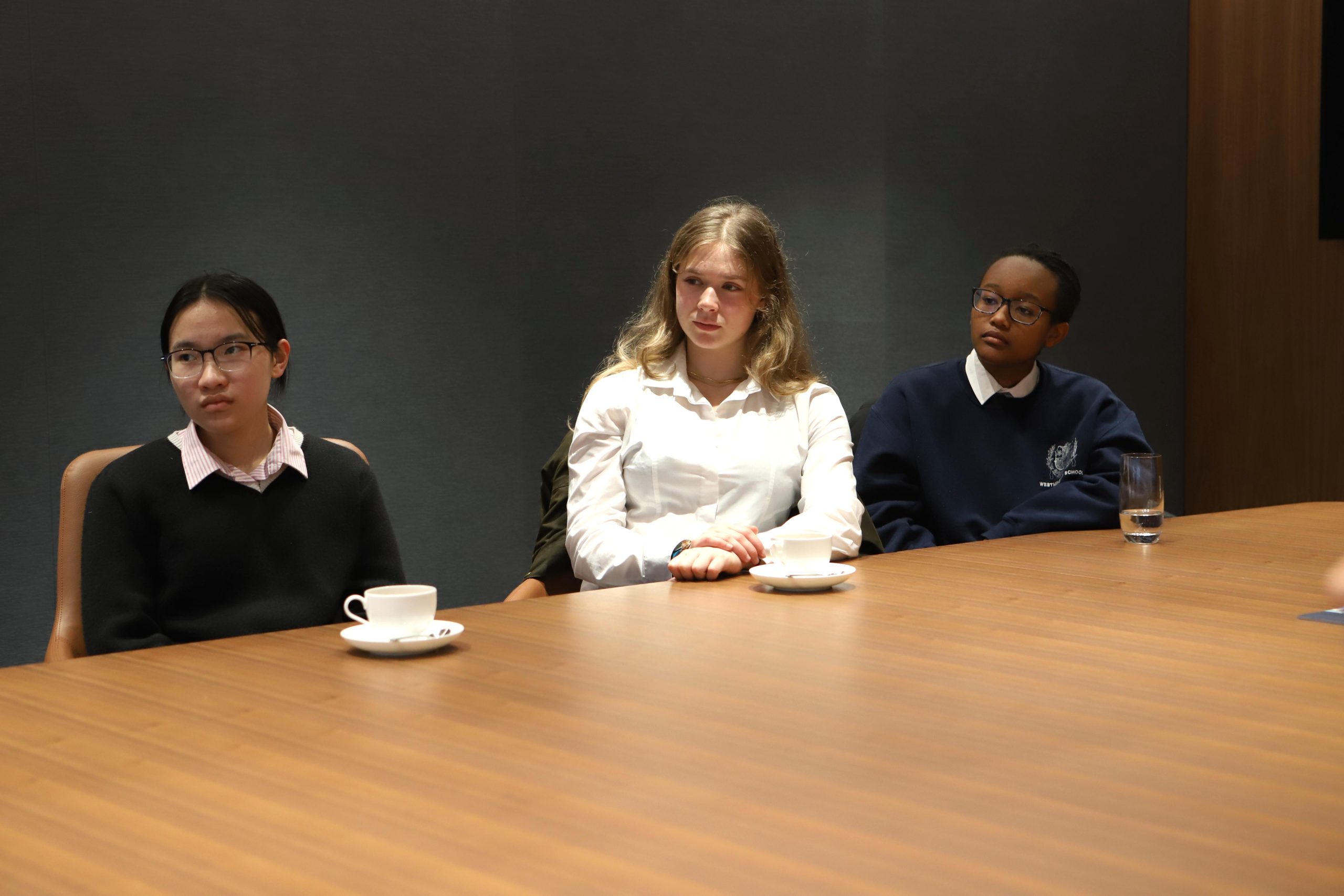 Three girls listening to one of the Lazard speakers in the board room