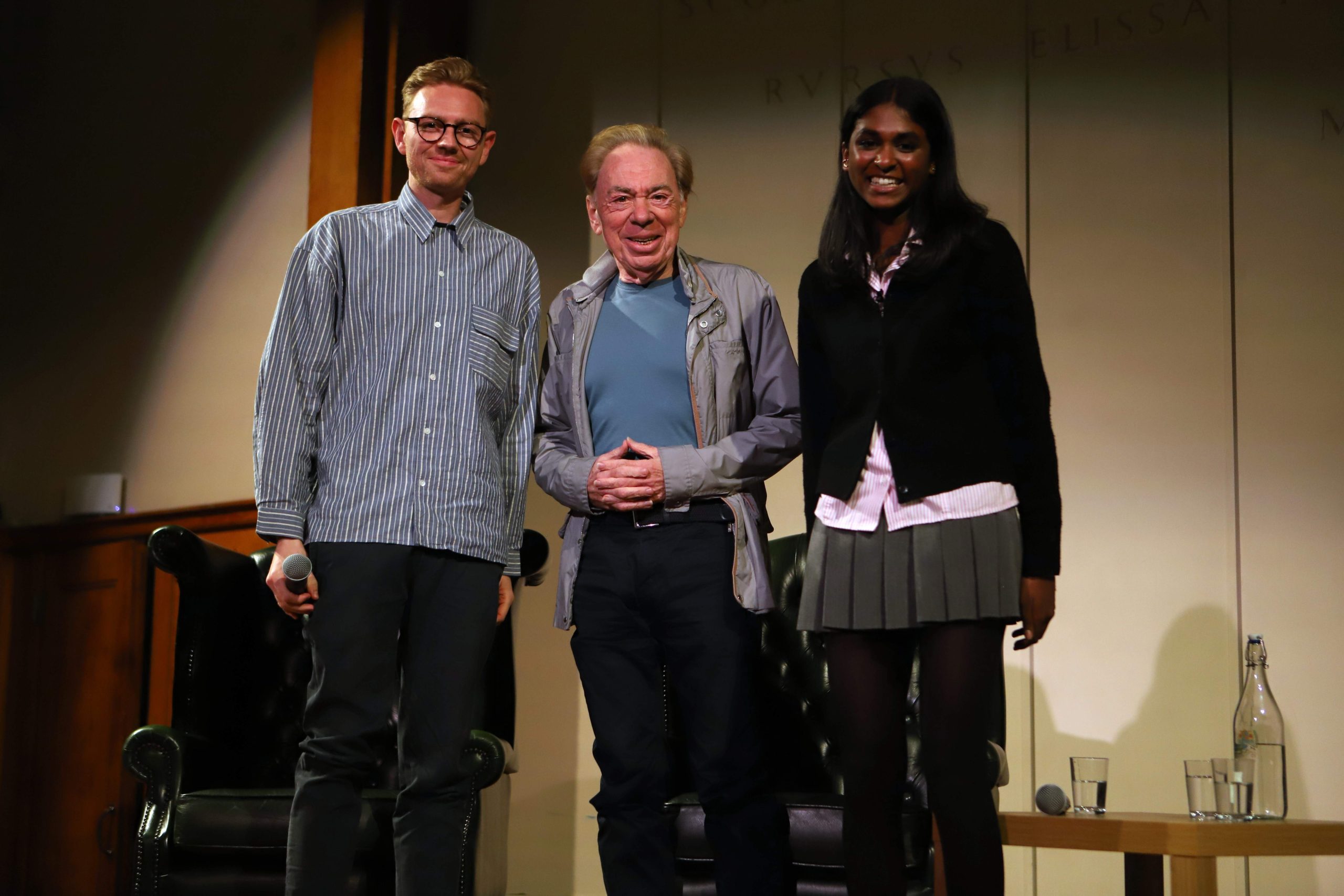 Lloyd Webber and his son Alastair standing on stage with Saathana smiling at the camera from above