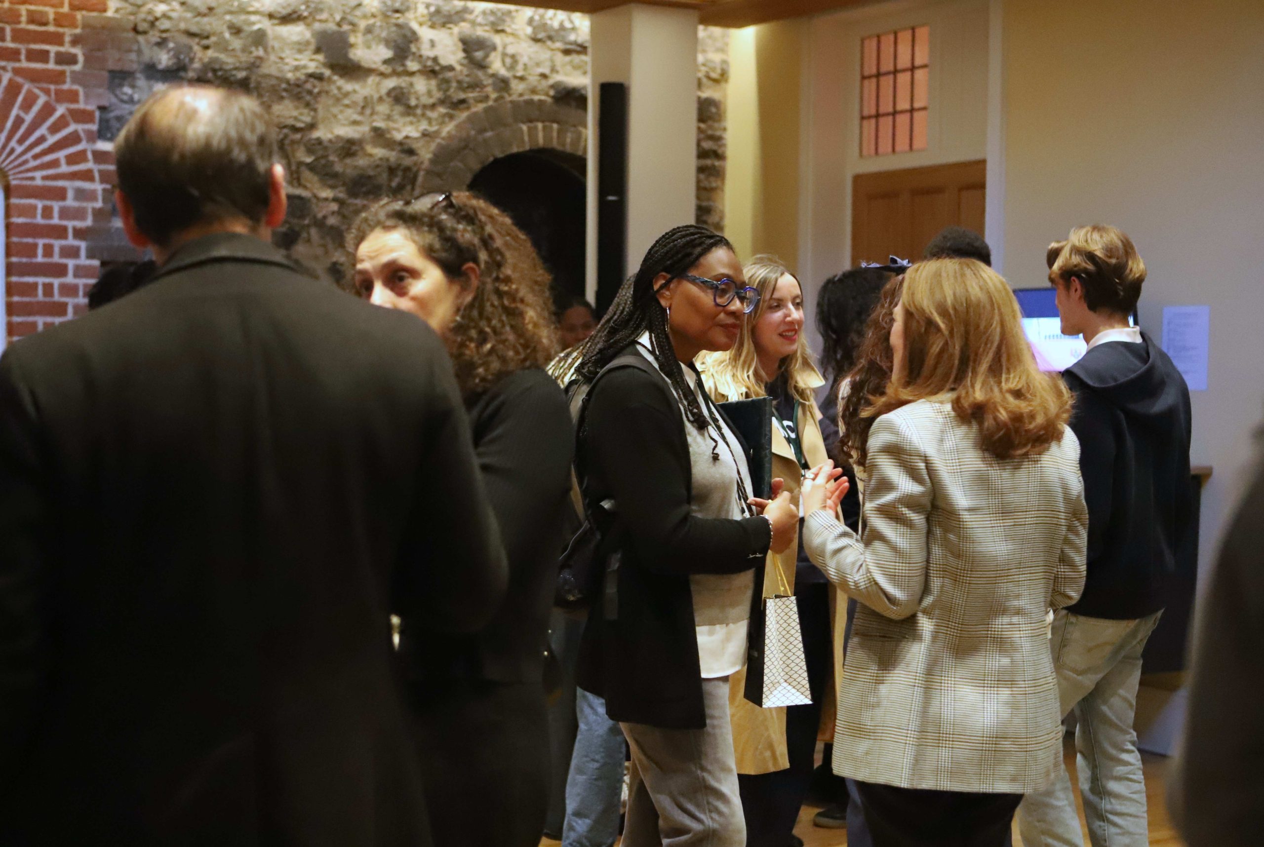 Teaching staff from Westminster and Martinique chatting together with an exposed stone wall in the background