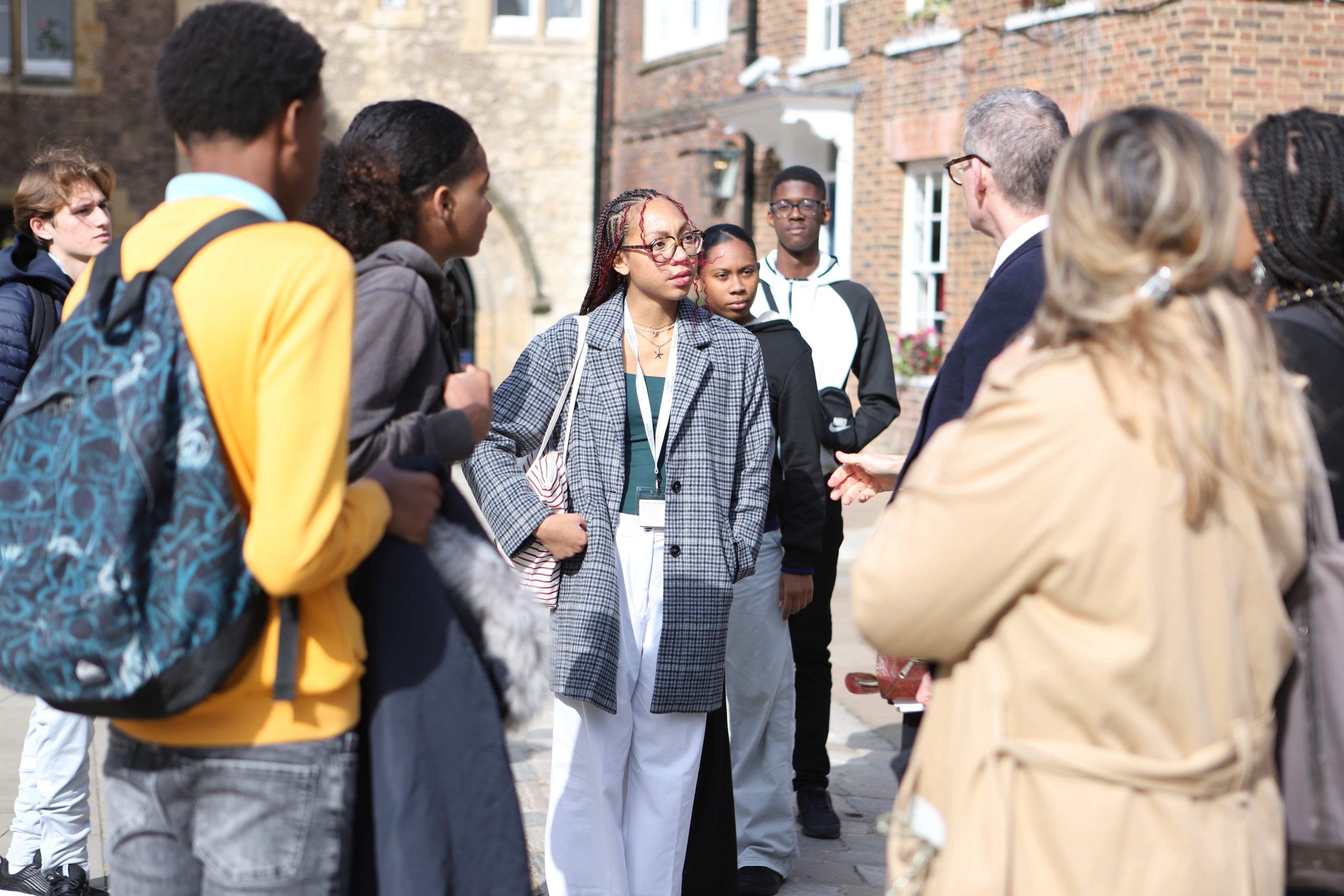 Martinique pupils in Little Dean's Yard hearing from their tour guide, there is a girl and the centre in white trousers and a checked jacket listening intently